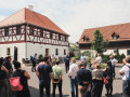 Viele Personen stehen im Innenhof eines Gebäudeensembles und hören zu. 